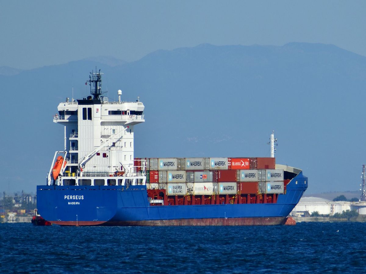 A container ship at sea with mountains behind